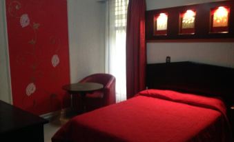 a hotel room with a red bed , white curtains , and a dark wooden desk near the window at Hotel Mexico