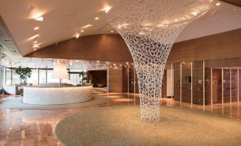 a modern hotel lobby with a white marble floor and a large sculpture of a wine bottle at Karuizawa Prince Hotel East