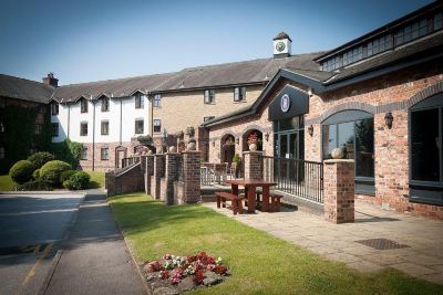 a brick building with a clock on the front and a patio area in front of it at Village Hotel Liverpool