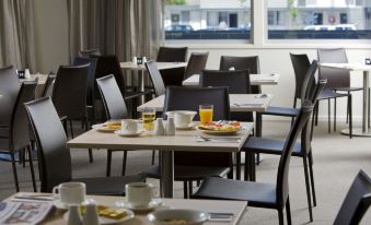 a dining room with several tables and chairs arranged for a group of people to enjoy breakfast at Ibis Styles Canberra Tall Trees
