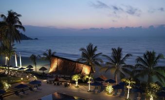 a large pool with palm trees and lounge chairs is surrounded by a building , creating a tropical atmosphere at Hyatt Regency Kuantan Resort