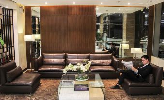 a brown leather couch is in a room with a glass coffee table and large windows at Brentwood Suites