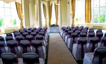 a wedding ceremony taking place in a large room , with rows of chairs arranged for guests at Cumbria Grand Hotel