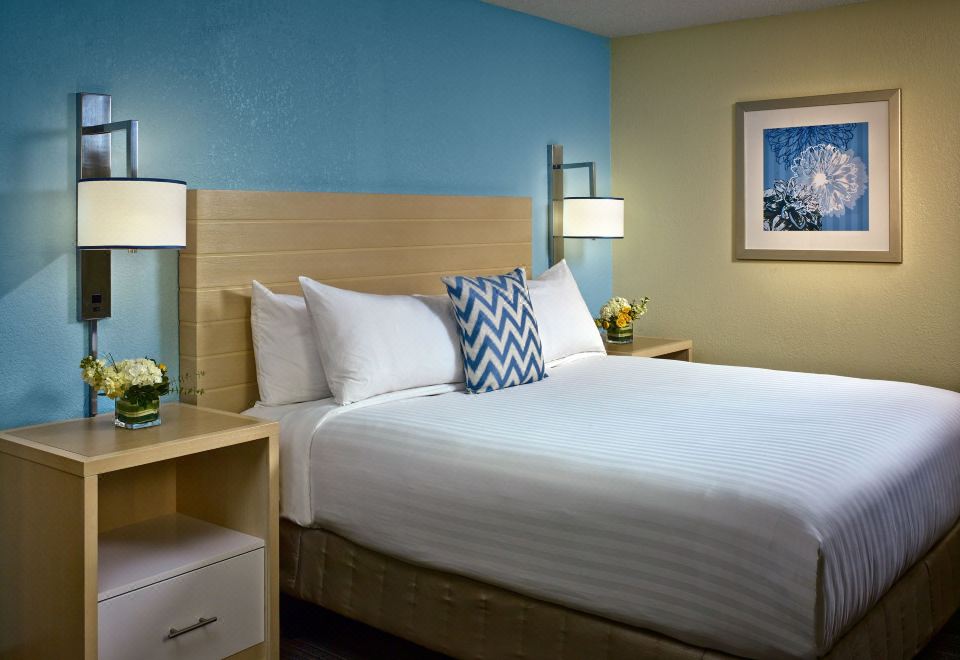 a large bed with white linens and a blue accent wall in a hotel room at Sonesta ES Suites Providence - Airport