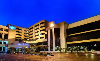 a large hotel building with a parking lot in front of it , illuminated at night at Chon Inter Hotel