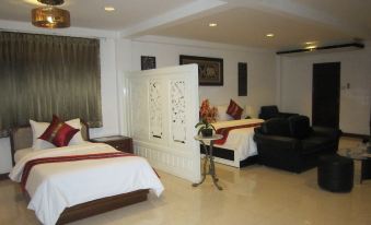 The bedroom has two beds and an open doorway that leads to the living area at True Siam Phayathai Hotel