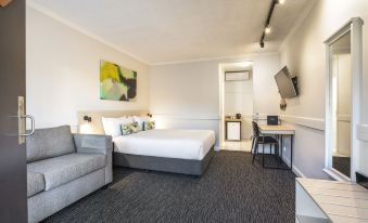 a modern hotel room with a large bed , couch , and tv , as well as a kitchenette at Nightcap at Matthew Flinders Hotel