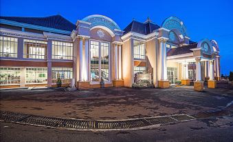 a large , modern building with multiple levels and large windows , surrounded by a parking lot at Royal Tretes View Hotel & Convention