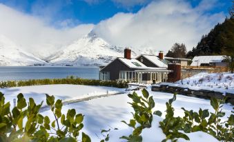 a snow - covered landscape with a house surrounded by mountains , creating a serene winter scene at Rosewood Matakauri