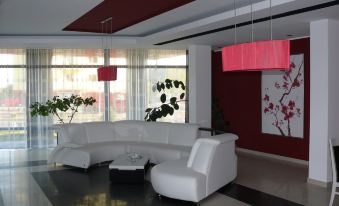 a modern living room with a white couch and chairs , red walls , and large windows at Black Tulip Hotel