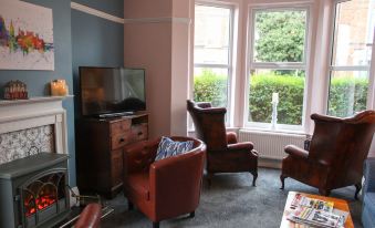 a cozy living room with various furniture , including a couch , chairs , and a television at The Linden Leaf Rooms - Classy & Stylish