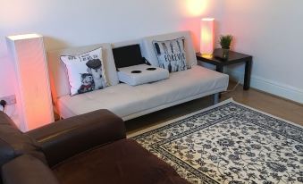 a living room with a couch , a chair , and a tv . also a dining table in the room at Town Apartments