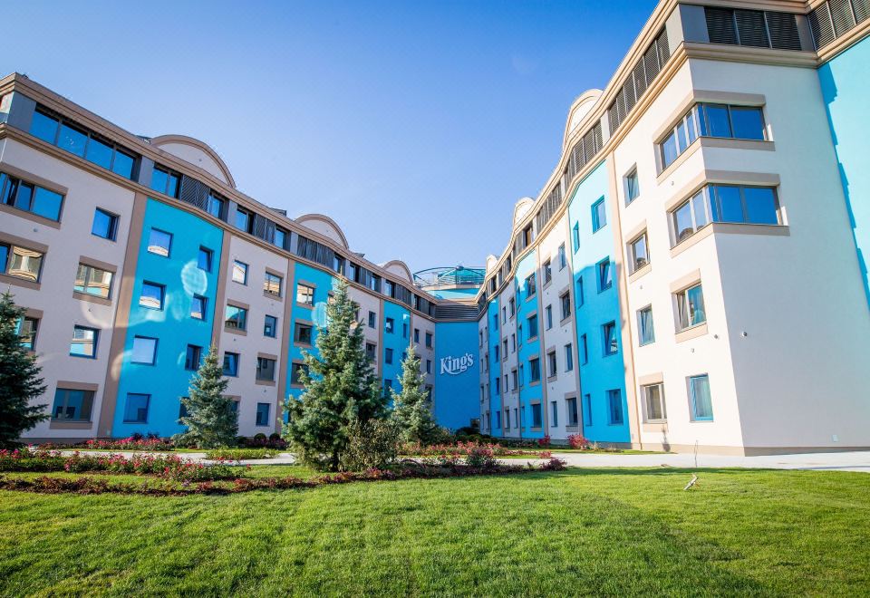 "a large building with blue and white walls , a sign that says "" new "". several trees in the foreground" at Kings Casino & Hotel