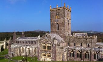 a large stone church with a tall tower and a grassy field in front of it at Ramsey House - Luxury Licensed B&B - Parking and Guest Lounge