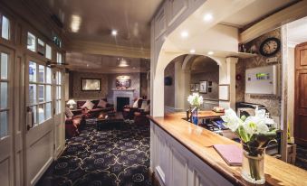 a cozy living room with a fireplace and a dining table , where people are sitting at chairs at Small Luxury Hotels of the World - the Mitre Hampton Court