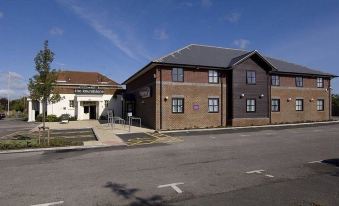 a two - story building with a brown roof and white trim , situated on a street corner at Premier Inn Littlehampton