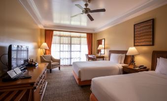 a modern hotel room with two beds , a dining table , and a balcony , all neatly arranged at The Manor at Camp John Hay