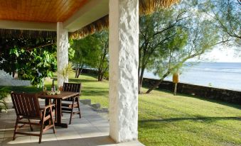 a patio with a table and chairs is set up next to a body of water at Mangaia Villas