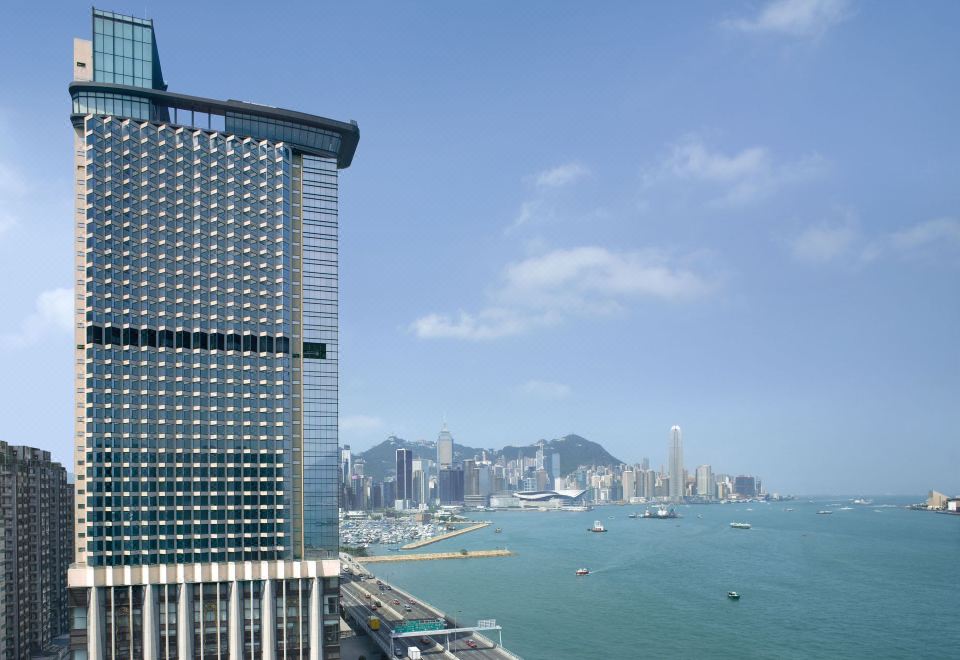 A spacious building with a view of the city skyline and waterfront, observed from the opposite side of the ocean at Harbour Grand Hong Kong