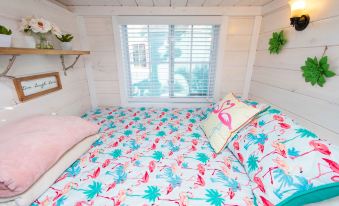 a cozy bedroom with a bed covered in a floral comforter and pillows , situated near a window at Matlacha Tiny Village