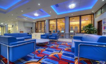 a large hotel lobby with blue couches and chairs , creating a comfortable seating area for guests at Alexandra Hotel
