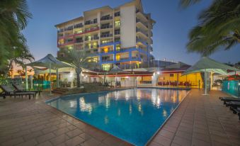 a large swimming pool is surrounded by lounge chairs and tables in front of a multi - story building at Mantra Mackay