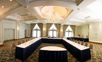 a large conference room with multiple long tables covered in blue tablecloths and chairs arranged around them at The Waterside Inn