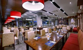 a restaurant with wooden tables and chairs , red hanging lights , and a counter in the background at ASTON Inn Mataram