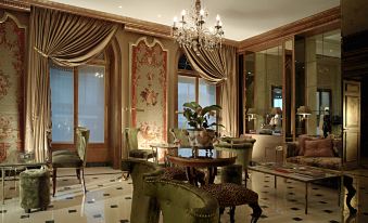 a luxurious hotel lobby with green leather chairs , a chandelier , and a chandelier hanging from the ceiling at Hotel d'Angleterre