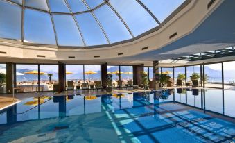 a large indoor swimming pool surrounded by lounge chairs , with a view of the ocean in the background at Le Mirador Resort and Spa