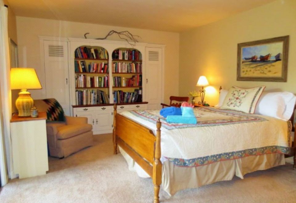 a cozy bedroom with a wooden bed , bookshelves , and lamps , creating a warm and inviting atmosphere at Three Pines