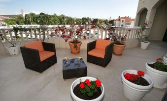 a rooftop patio with several chairs and potted plants , creating a cozy outdoor seating area at Hotel Bellevue Trogir
