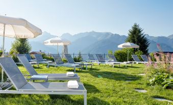 a grassy area with several lounge chairs and umbrellas , providing a relaxing environment for guests at Schlosshotel Fiss