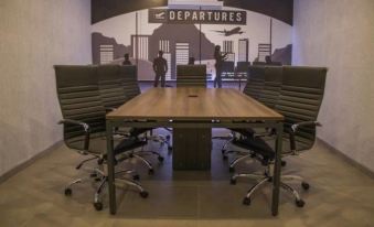 a conference room with a large wooden table surrounded by black chairs and a mural of airplanes at Hangar Inn Guadalajara Aeropuerto