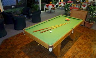 a billiards table with green felt and pool sticks in an outdoor setting , surrounded by outdoor dining furniture at Lindy Lodge Motel