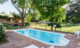 a backyard with a swimming pool surrounded by trees , chairs , and a barbecue grill , providing a relaxing outdoor space at Berrima Bakehouse Motel