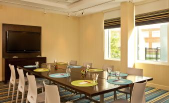 a dining room with a long table set for a meal , complete with plates , cups , and utensils at Aloft Chesapeake