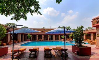 a large outdoor swimming pool surrounded by lounge chairs and umbrellas , providing a relaxing atmosphere for guests at Faisalabad Serena Hotel