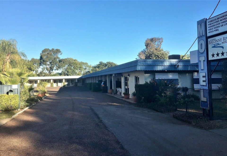 a blue building with a blue roof and a road in front of it , surrounded by trees at Balonne River Motor Inn