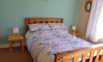 a cozy bedroom with a wooden bed , blue walls , and a clock on the wall at The Loft