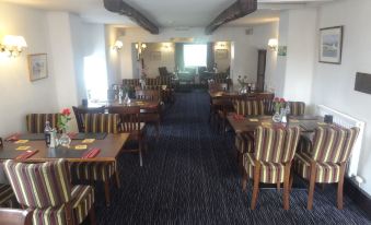 a large , empty dining room with multiple tables and chairs arranged for a group of people at The Shepherds Inn