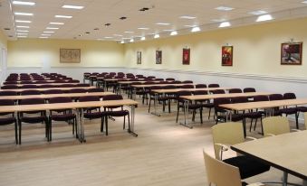 "a large , empty conference room with multiple rows of tables and chairs , each table having a chair labeled "" business "" and "" finance ""." at Hotel Berg