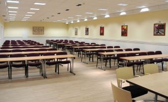 a large , empty conference room with multiple tables and chairs arranged for a meeting or event at Hotel Berg