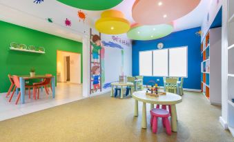 a colorful playroom with multiple tables and chairs , as well as a few potted plants at Emotions by Hodelpa - Juan Dolio