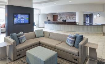 a hotel lobby with a large couch , a television , and a reception desk in the background at Courtyard Carolina Beach Oceanfront