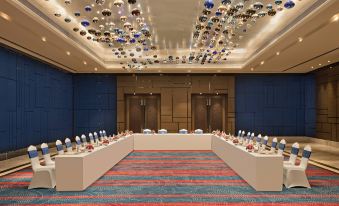 a large conference room with a long table and multiple rows of chairs arranged for a meeting at Sheraton Grand Bengaluru Whitefield Hotel & Convention Center