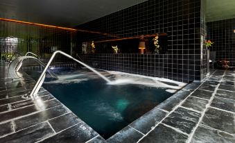 a black and white tiled indoor pool with a waterfall feature , creating a unique and inviting atmosphere at Douro Palace Hotel Resort & Spa