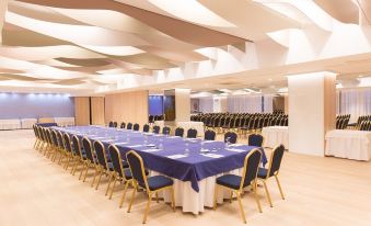 a large conference room set up for a meeting , with multiple tables and chairs arranged in a semicircle at Hotel Olympia Valencia