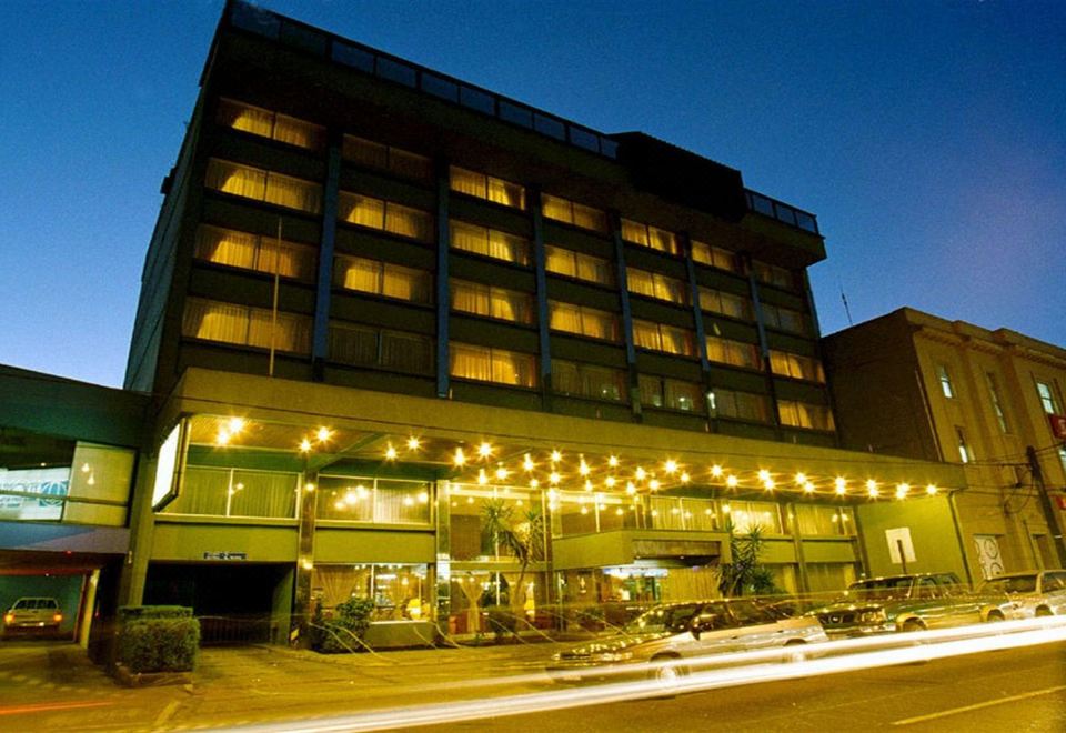 a large hotel building with many windows , surrounded by trees and lit up at night at Hotel Frontera Clásico