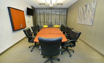 a conference room with a large orange table surrounded by black chairs and a tv mounted on the wall at SpringHill Suites Grand Forks